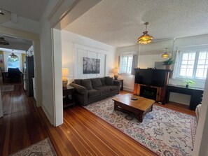 Ein Wohnzimmer mit Sofa, Couchtisch, Fernseher, Kamin und einem Essbereich mit Stühlen und Tisch.
