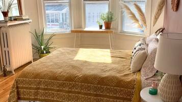 Ein Schlafzimmer mit einem großen Bett, einem kleinen Tisch und einem Fenster mit Jalousien.