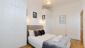 Un dormitorio con cama, armario blanco y radiador.