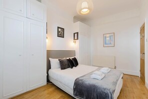 Ein Schlafzimmer mit Bett, weißem Kleiderschrank und Heizkörper.