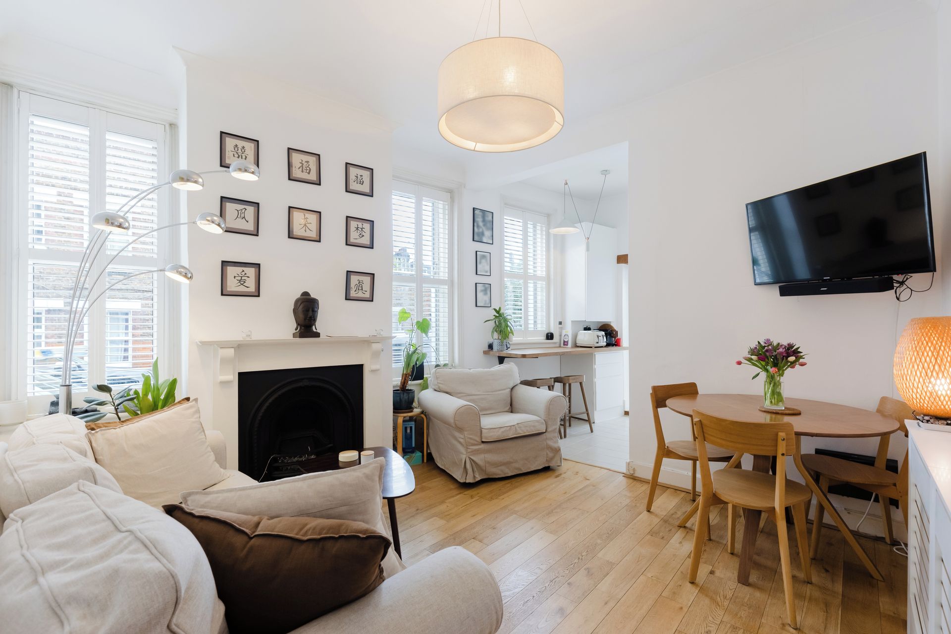 Una sala de estar moderna con chimenea, una zona de comedor y una cocina al fondo.