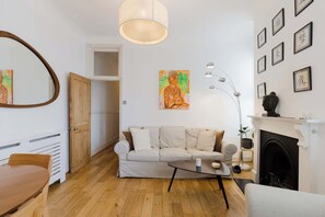 Ein Wohnzimmer mit Sofa, Couchtisch, Kamin und Kunstwerken an den Wänden.