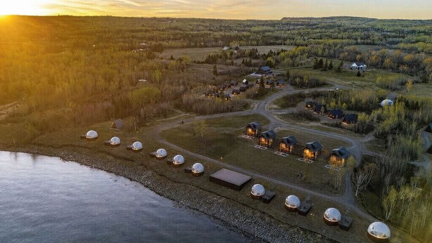 A lakeside property with yurts and cabins, a winding road, and a forested landscape.