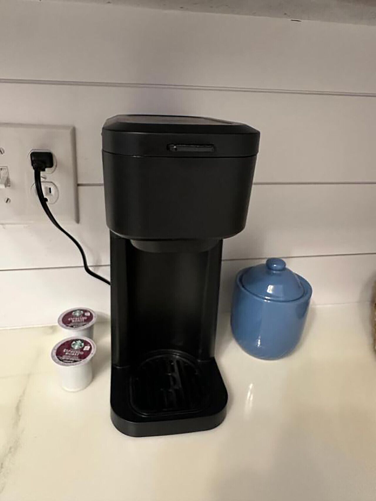Een koffiezetapparaat op een aanrecht, met een stopcontact en twee bakken.