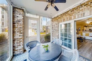 A patio with a round table, chairs, and a ceiling fan. - Lakefront 3br Luxury Condo - MB (Myrtle Beach)