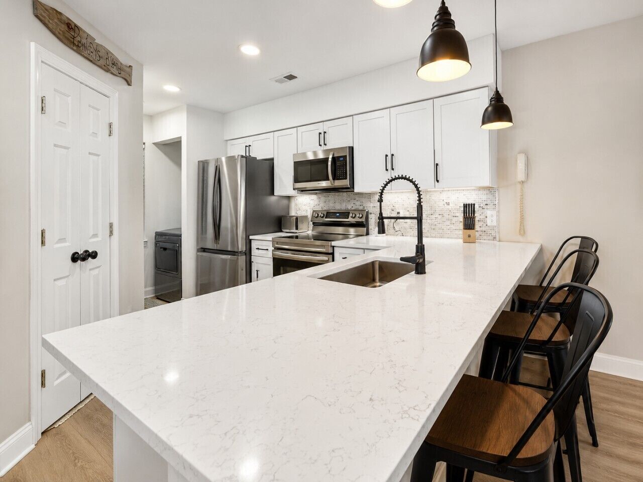 A modern kitchen with white cabinetry, stainless steel appliances, and a marble island.