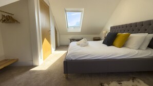Ein Schlafzimmer mit einem Bett, einem Oberlicht, einer hölzernen Bank und einem Fellteppich.