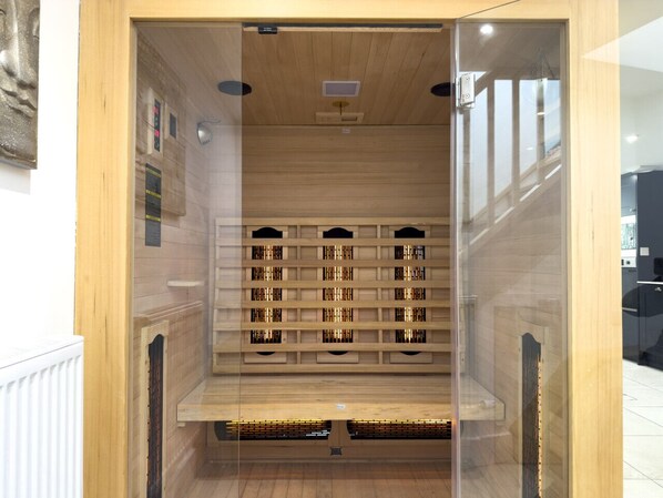 Un sauna avec des bancs en bois et une porte en verre.