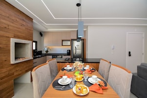 Un comedor moderno con una mesa de madera, sillas y una cocina al fondo.