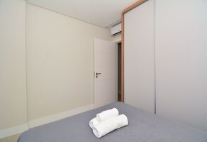Un dormitorio con cama, una puerta y un equipo de aire acondicionado.