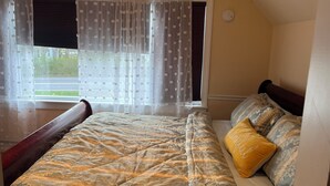 A bedroom with a bed, a window with curtains, and a view of the outdoors. - Limbe Guest House in Latham NY (Latham)