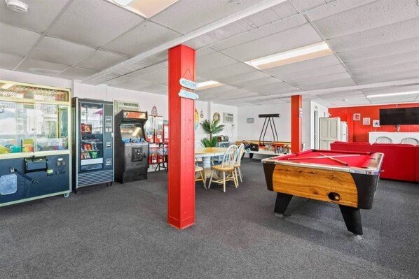 A recreational room with a pool table, arcade games, and a billiards table.