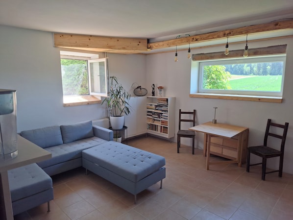 Una sala moderna con un sofá seccional, una mesa de comedor de madera y una estantería.