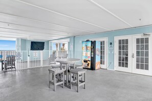 A poolside area with a covered seating area, a vending machine, and a door to the pool. - Renovated 1-bedroom condo in lovely Orange Beach (Orange Beach)