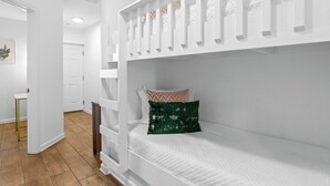 Una cama litera con escalera, una mesita de noche y un almohadón con diseño geométrico.