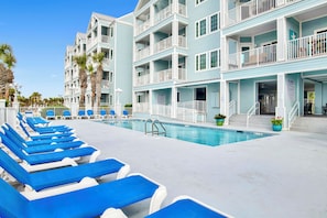 A hotel with a pool area, multiple balconies, and lounge chairs. - Renovated 1-bedroom condo in lovely Orange Beach (Orange Beach)