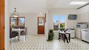 Uma cozinha moderna com armários brancos, micro-ondas e um espaço de jantar com mesa e cadeiras.