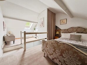 A bedroom with a bed, a nightstand, a lamp, a window, and a staircase leading to an outdoor area. - Charress House, 6/7 Bedrooms, 10 beds, 3 bathrooms Contractors/Friends/Families. (Whitwell)