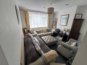 A living room with a sofa, armchair, ottoman, television, and a cabinet.