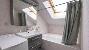 Ein modernes Badezimmer mit Dachfenster, einer Badewanne und einem Waschtisch.