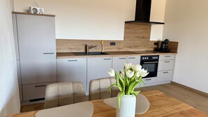 Une cuisine moderne avec un plan de travail en bois, un four encastré et un vase blanc orné de fleurs sur la table à manger.