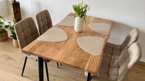 Une table à manger avec quatre chaises, un vase rempli de fleurs et un plancher en bois.