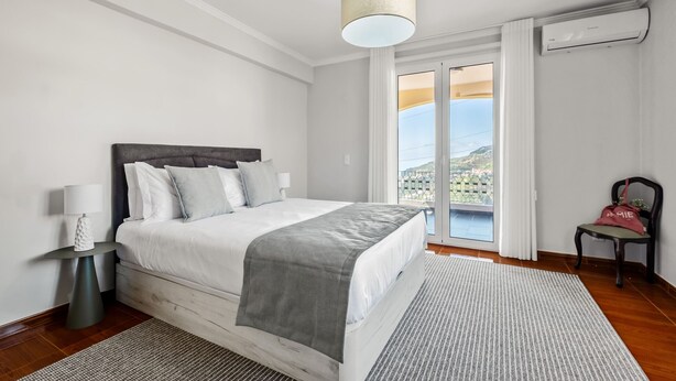 Una camera da letto moderna con un letto, un comodino, una lampada e vista sull'esterno.