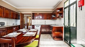 Cucina con mobili in legno, un tavolo da pranzo apparecchiato con piatti e bicchieri, un forno a microonde ed una lavastoviglie.