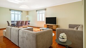 Un soggiorno moderno con un divano componibile, una televisione e un'area pranzo con sedie e tavolo.