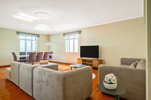 A modern living room with a sectional sofa, a TV, and a dining area with chairs and a table. - Villa Vineyard by Homie (Câmara de Lobos)