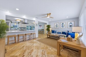 Ein modernes Wohnzimmer mit einer Couch, einem Couchtisch und einem Essbereich mit Barhocker.
