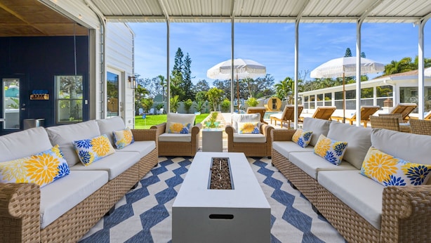A covered outdoor seating area with wicker furniture and a central coffee table. - NEW - Sweet St Pete - 5 Minutes to beach - Heated Pool, Hot Tub, Sauna, + more (St. Petersburg)