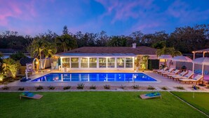 A modern house with a swimming pool, outdoor lounge chairs, and a well-maintained lawn. - NEW - Sweet St Pete - 5 Minutes to beach - Heated Pool, Hot Tub, Sauna, + more (St. Petersburg)
