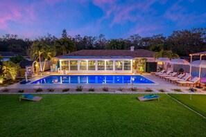 Ein modernes Haus mit Swimmingpool, Liegestühlen im Freien und einem gepflegten Rasen.