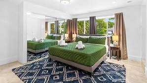A hotel room with two beds, a large window, a mirror, and a patterned rug. - Boho Villa by Glam Homes (Miami)