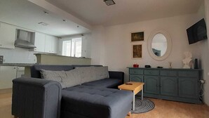 Ein stilvolles Wohnzimmer mit Sofa, einem kleinen Tisch, einem Schrank und einem Fernseher.
