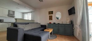 Un espace de vie moderne comprenant un canapé, une petite table, un meuble et un téléviseur.