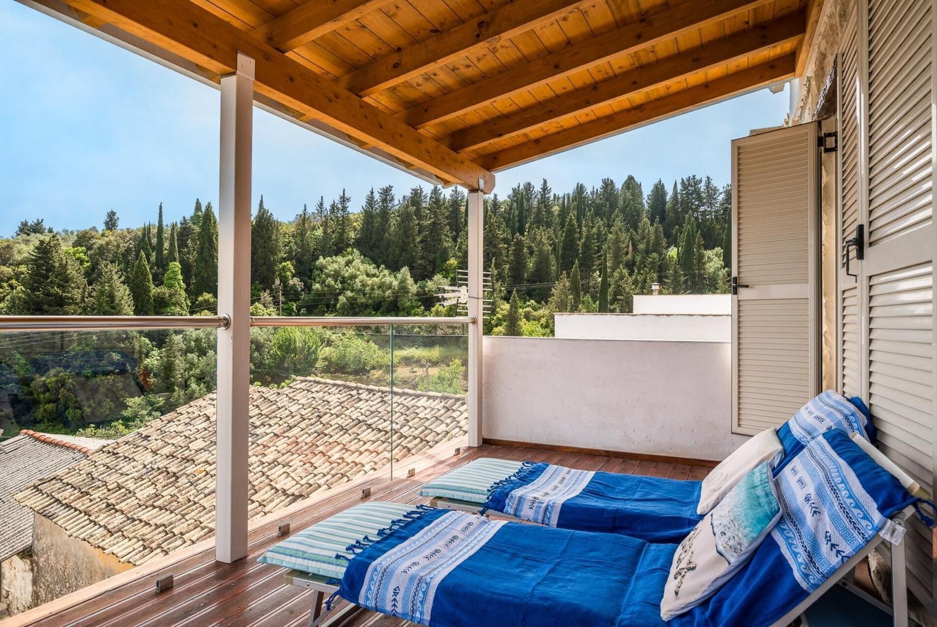 Ein Balkon mit zwei Betten, einer Holzbalkendecke und Blick auf ein bewaldetes Gebiet.