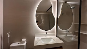 A modern bathroom with a toilet, sink, and mirror. - Setai Aquamares - Miramar Hospedagens (João Pessoa)