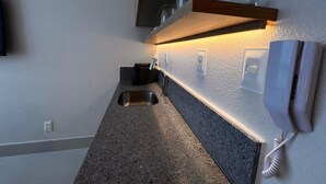 A kitchen with a granite countertop, a stainless steel sink, a built-in oven, and a wall-mounted telephone. - Setai Aquamares - Miramar Hospedagens (João Pessoa)