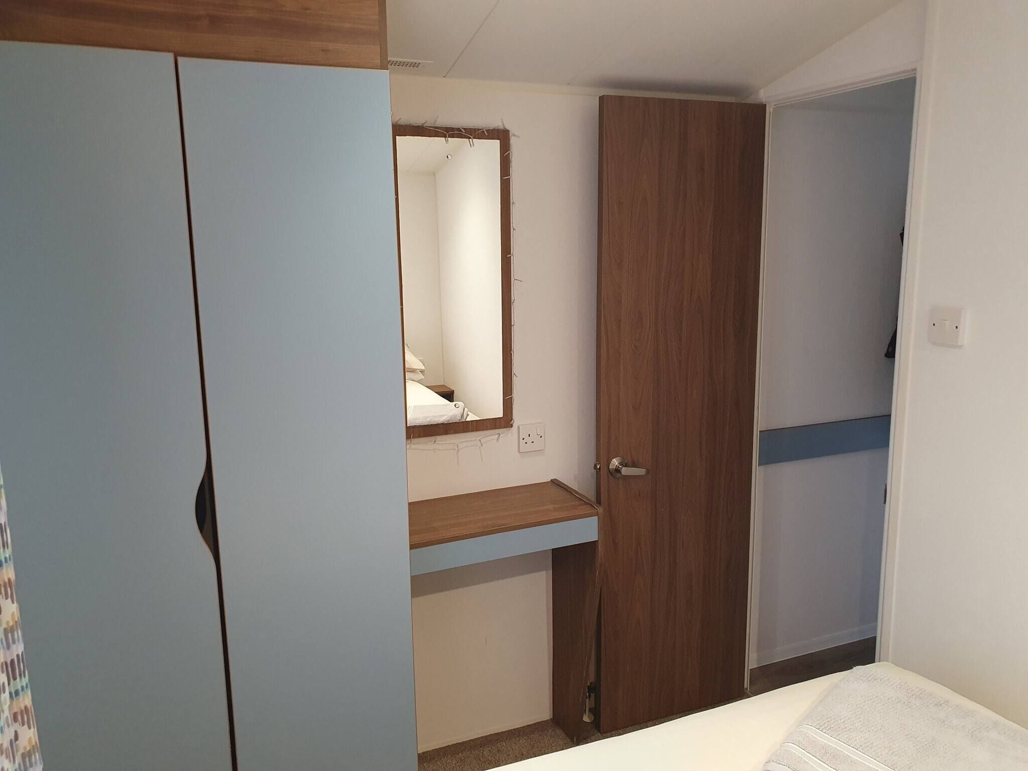 Ein Schlafzimmer mit Bett, Kleiderschrank, Spiegel und Tür.