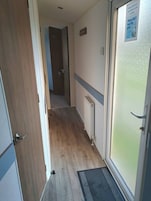 Un pasillo con suelo de madera, un radiador y una puerta con ventana de vidrio esmerilado.