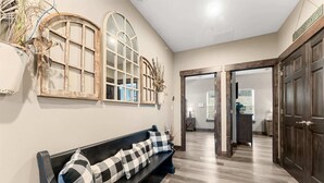 Un corridoio con una panca, porte in legno e una parete con cornici decorative per finestre.
