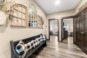 Un pasillo con un banco, puertas de madera y una pared con marcos de ventana decorativos.