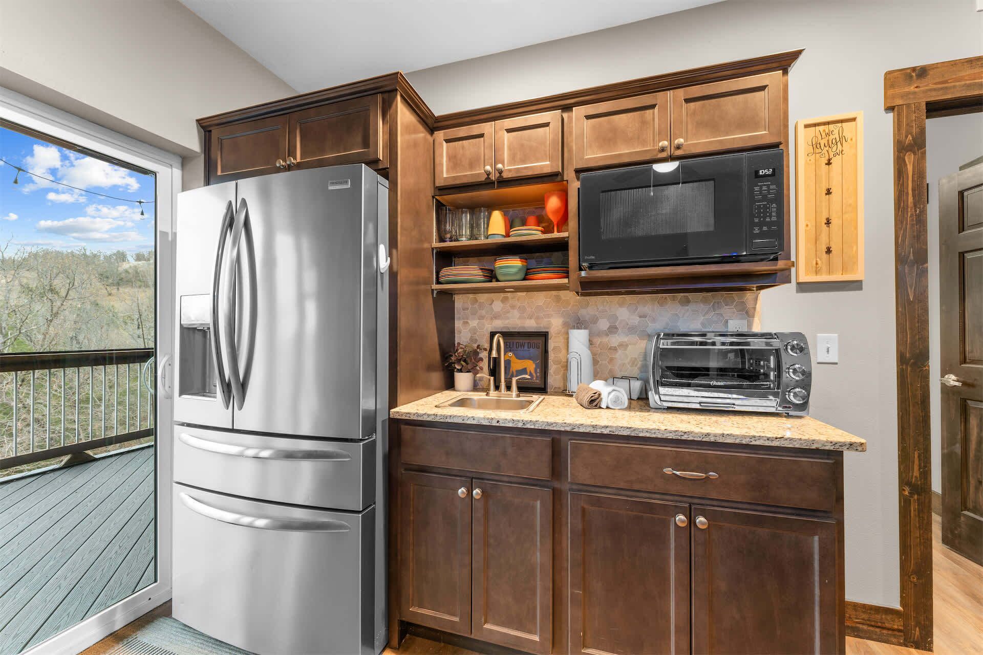 A kitchen with a stainless steel refrigerator, a microwave, a toaster, and wooden cabinets.