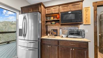 A kitchen with a stainless steel refrigerator, a microwave, a toaster, and wooden cabinets.