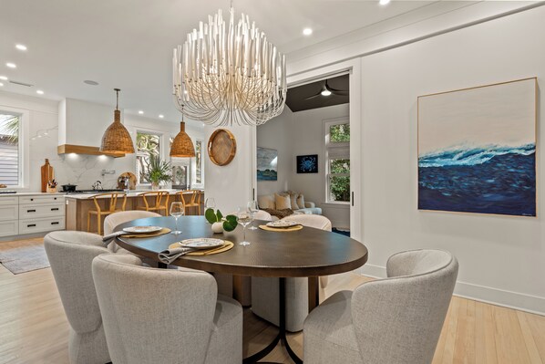 A modern dining area with a round table, chairs, and pendant lighting.