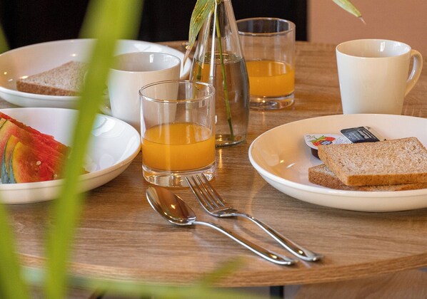 A breakfast setting with a plate of toast, a glass of orange juice, and a cup of tea.