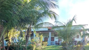 A house with a white exterior, a balcony, and a garden with palm trees and flowers. - Guesthouse facing Silves, 5 minutes from the bus terminal, with river access. (Silves)