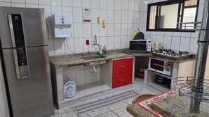 A kitchen with a refrigerator, microwave, stove, sink, and red cabinets. - APARTMENT IN PRAIA GRANDE – VILA TUPI | COMFORT, LOCATION AND INCREDIBLE VIEW (Praia Grande)